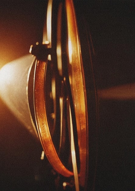 A close-up shot of a classic film reel, partially unwound, with a beam of light shining through the celluloid, highlighting the texture and artistry of filmmaking.